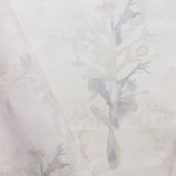 Detail of draped fabric yardage in an abstract botanical print in shades of tan and gray on a white field.