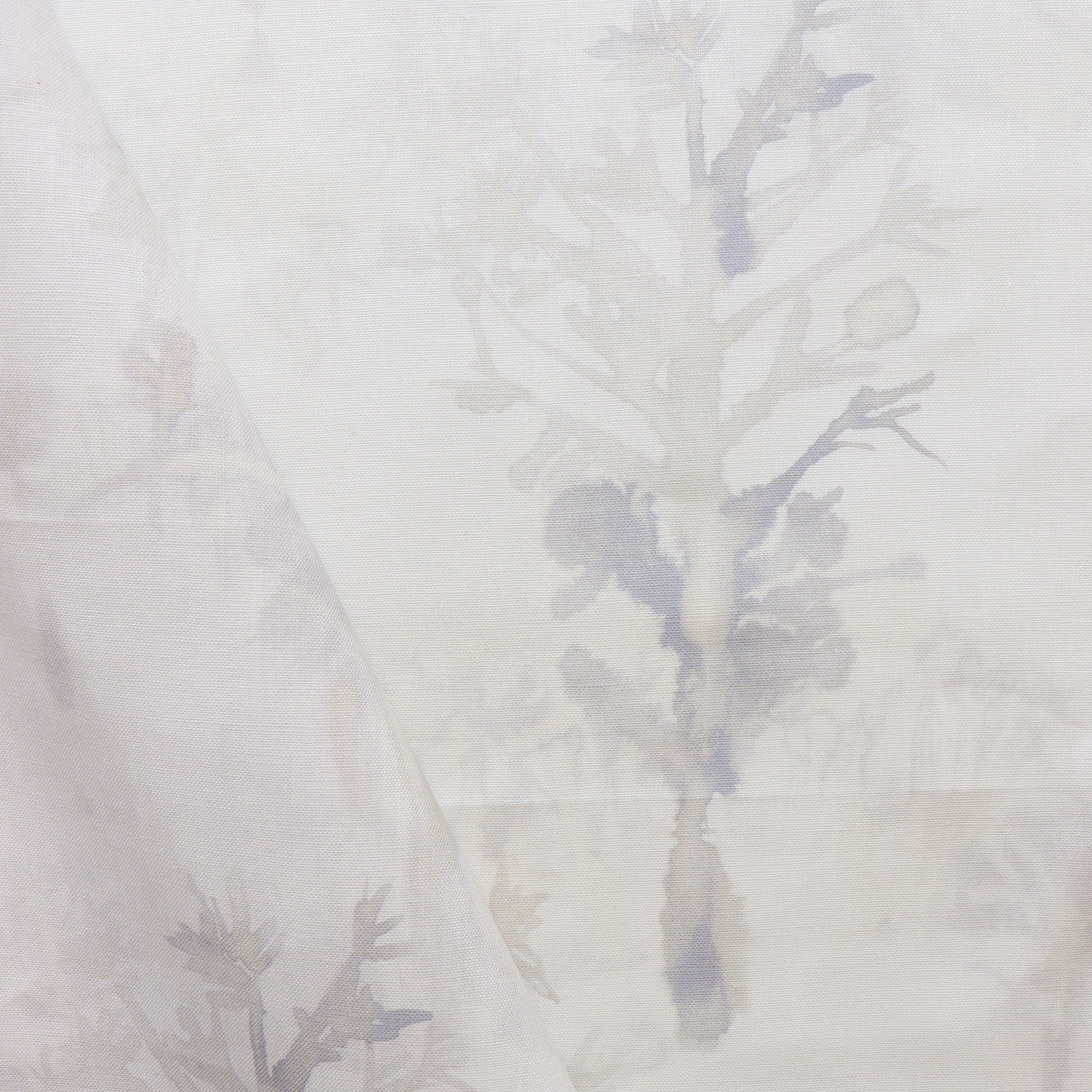 Detail of draped fabric yardage in an abstract botanical print in shades of tan and gray on a white field.