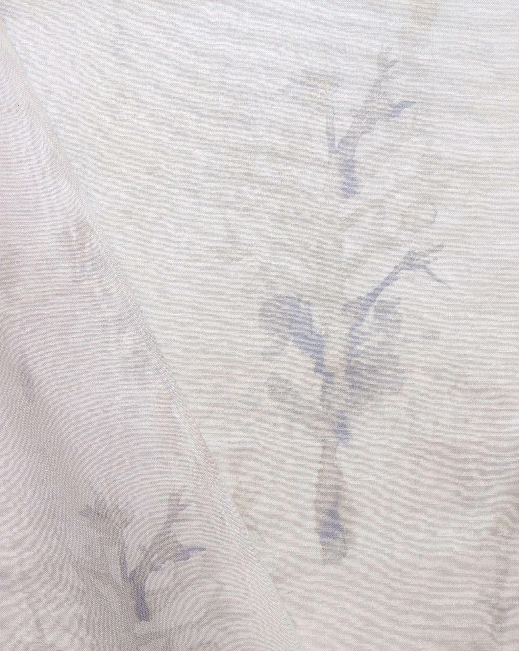 Detail of draped fabric yardage in an abstract botanical print in shades of tan and gray on a white field.