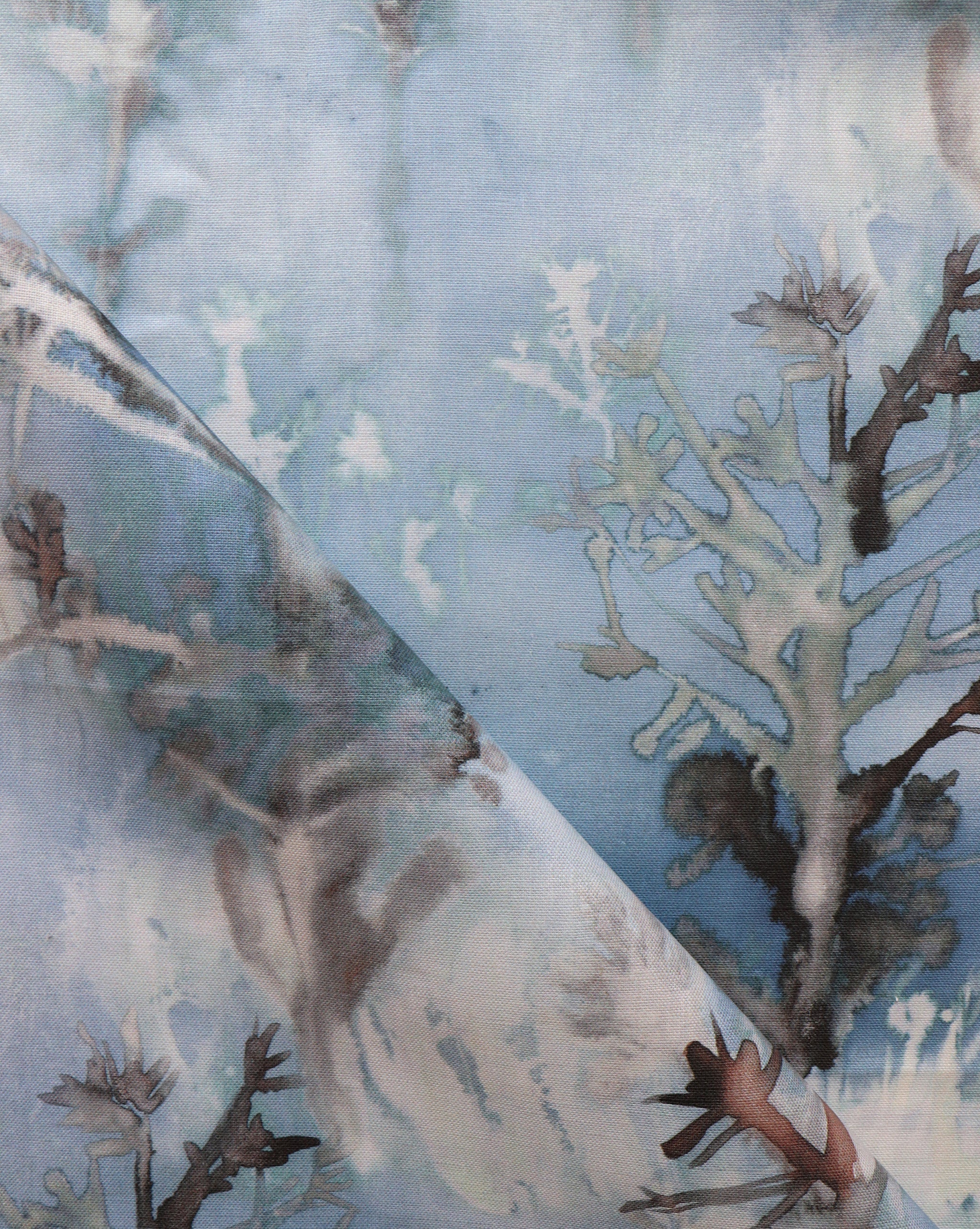 Detail of draped fabric yardage in an abstract botanical print in shades of gray and turquoise on a blue field.