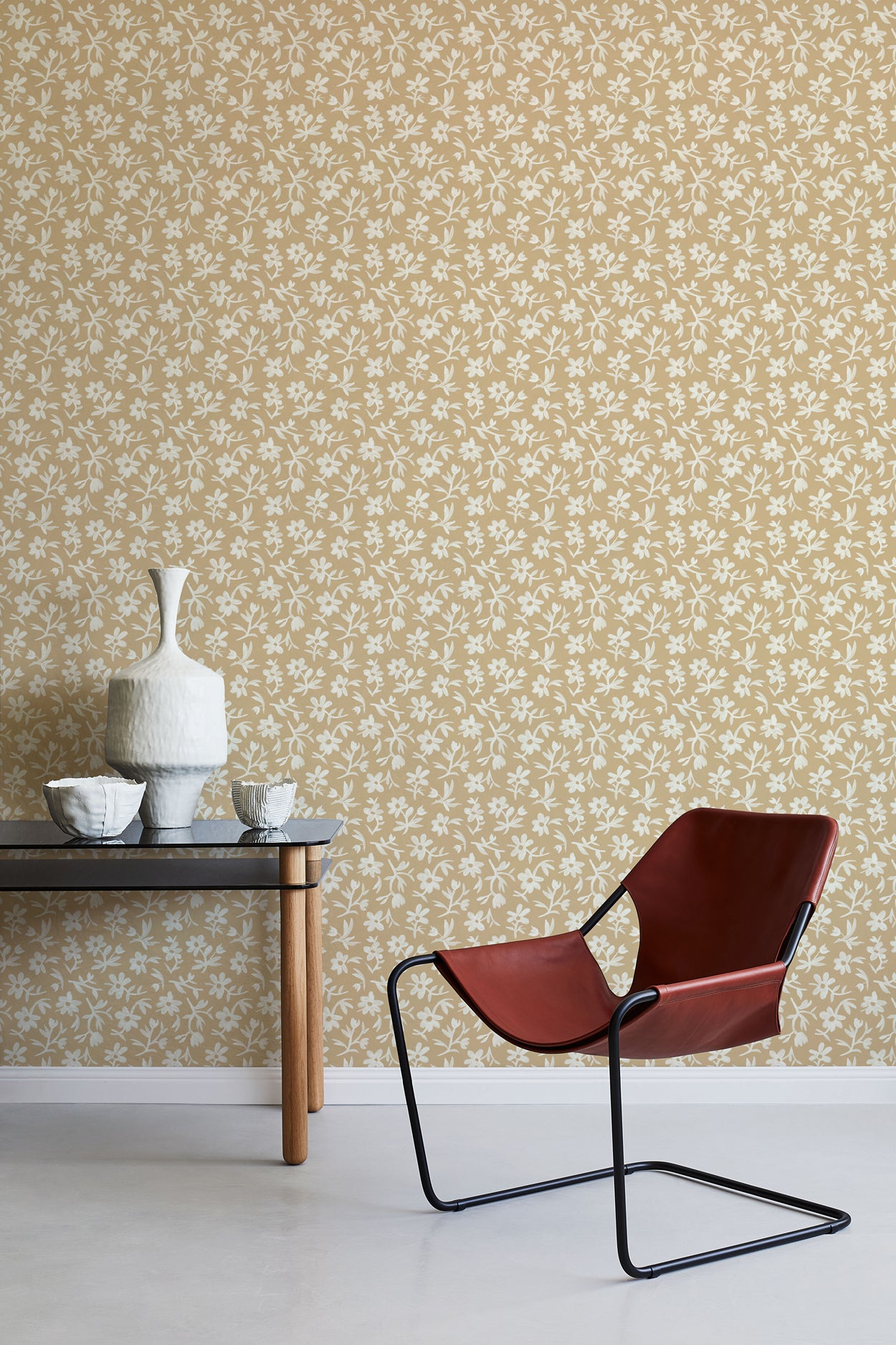 Modern chair and table against a white and tan floral wallpapered wall.