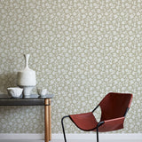 Modern chair against a floral wallpapered wall with a small table and decorative items.