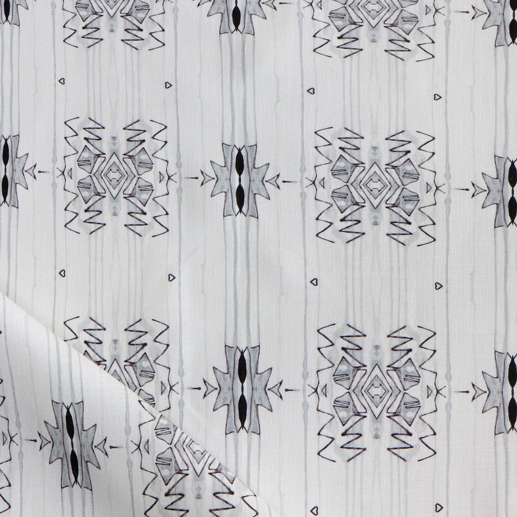 Detail of draped fabric yardage in a minimalist ikat pattern in shades of gray on a white field.