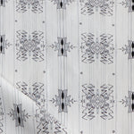 Detail of draped fabric yardage in a minimalist ikat pattern in shades of gray on a white field.