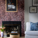 A maximalist living room tableau with a statement wall papered in an abstract textural print in red, gray and black.