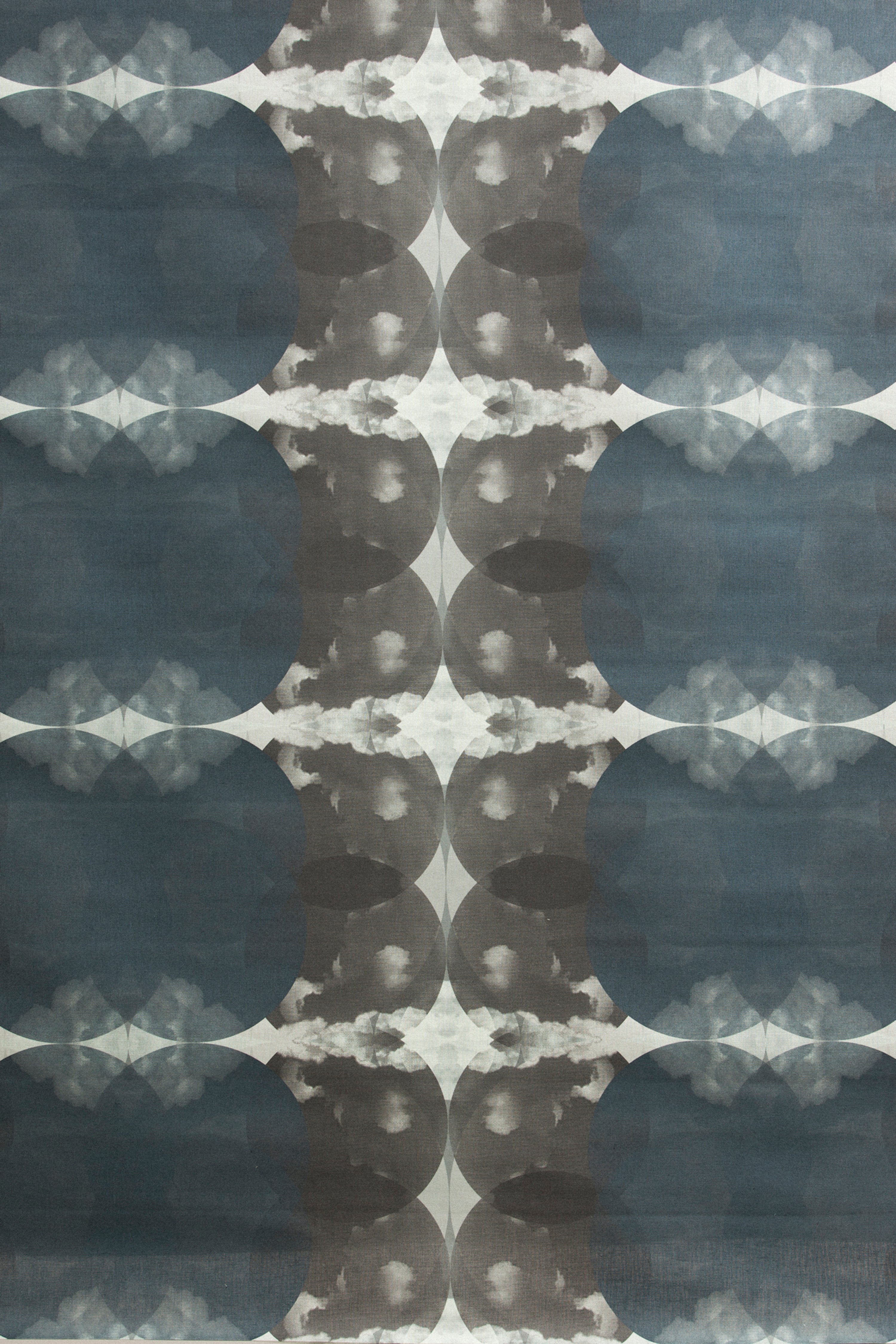 Detail of fabric in a cloudy ink blot print in shades of gray and blue on a light gray field.