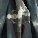 Crumpled fabric yardage in a cloudy ink blot print in shades of gray and blue on a light gray field.