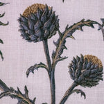 Detail of fabric in a repeating artichoke print in shades of purple, brown and green on a light purple field.