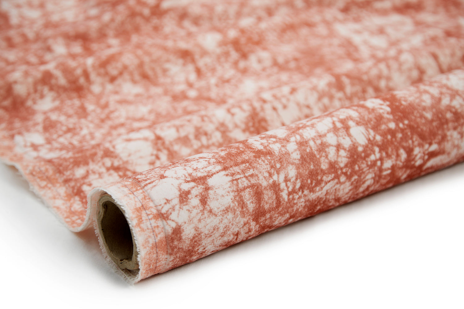 Partially unrolled fabric in an organic crumpled texture in coral on a cream field.
