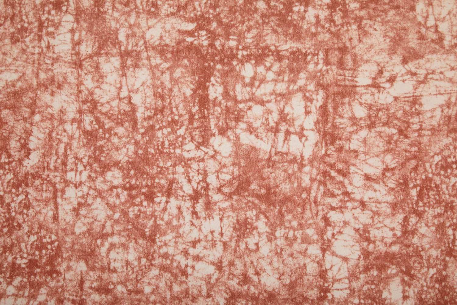 Detail of velvet fabric in an organic crumpled texture in coral on a cream field.