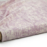 Partially unrolled fabric in an organic crumpled texture in light purple on a cream field.