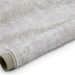 Partially unrolled fabric in an organic crumpled texture in light gray on a cream field.