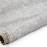 Partially unrolled fabric in an organic crumpled texture in light gray on a cream field.