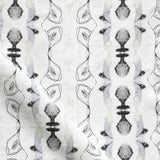 Detail of draped fabric yardage in a watercolor ikat stripe print in shades of gray and black on a white field.