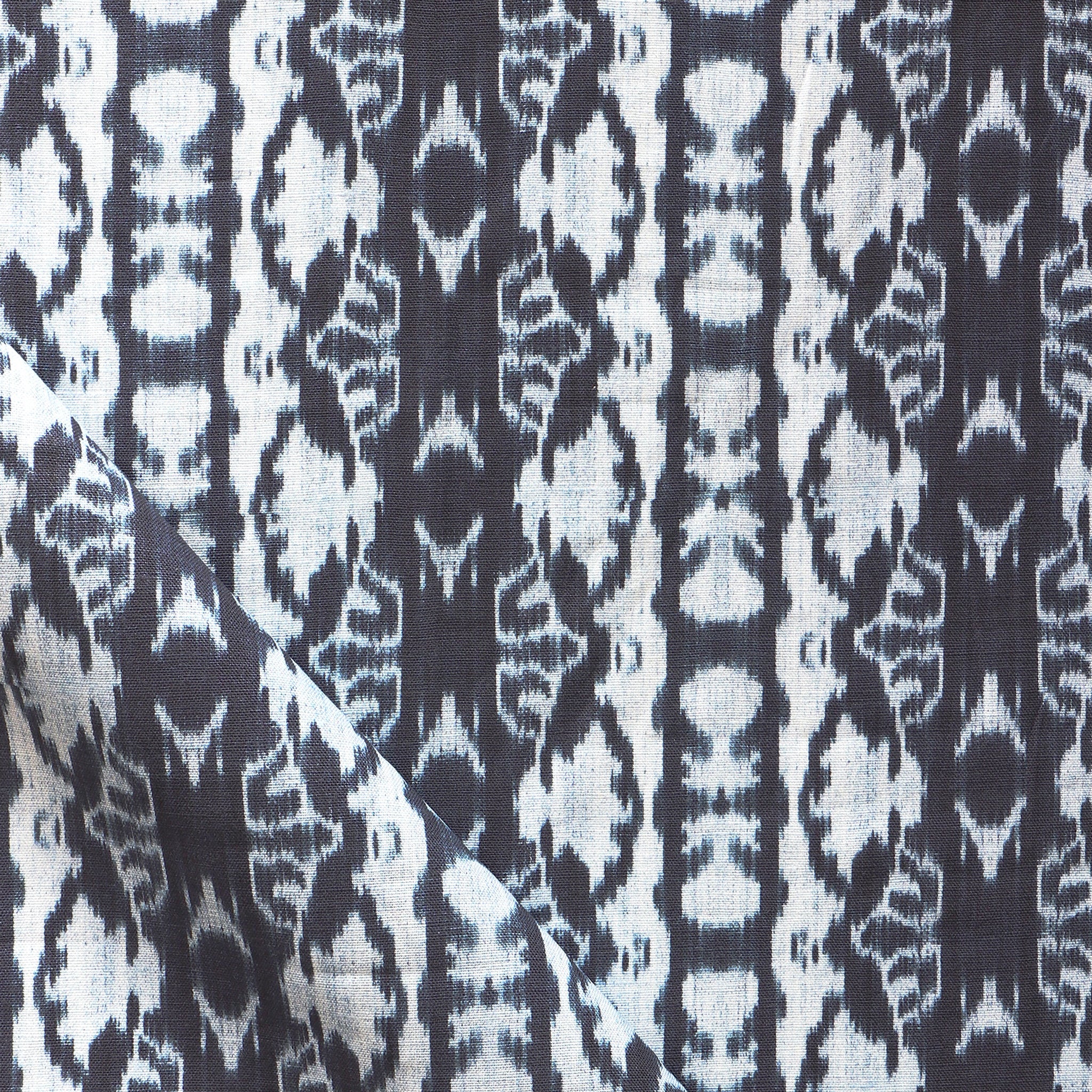 Detail of draped fabric yardage in an abstract ikat stripe print in shades of white and blue on a gray field.