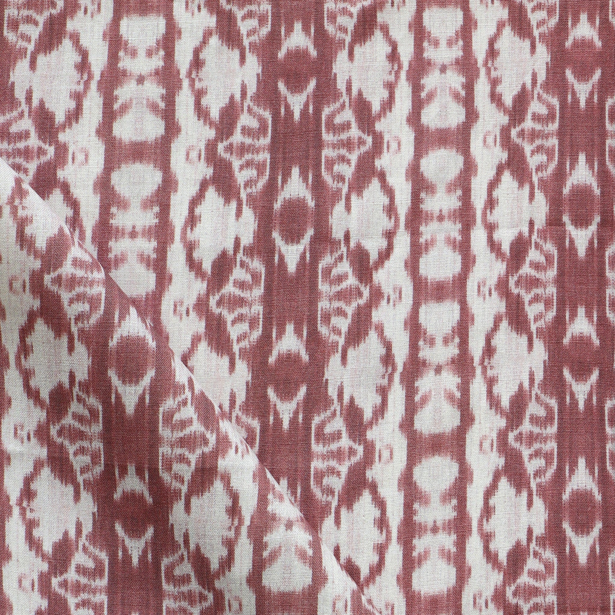 Detail of draped fabric yardage in an abstract ikat stripe print in shades of white on a red field.