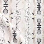 Detail of draped fabric yardage in an abstract ikat stripe print in shades of cream, pink and gray on a white field.