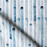 Detail of draped fabric in a painterly stripe print in blue on a white field.