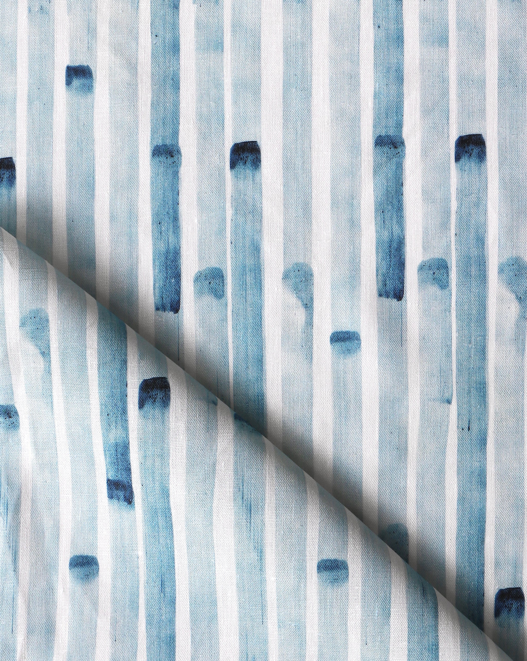 Detail of draped fabric in a painterly stripe print in blue on a white field.