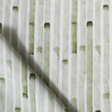 Detail of draped fabric in a painterly stripe print in olive on a white field.