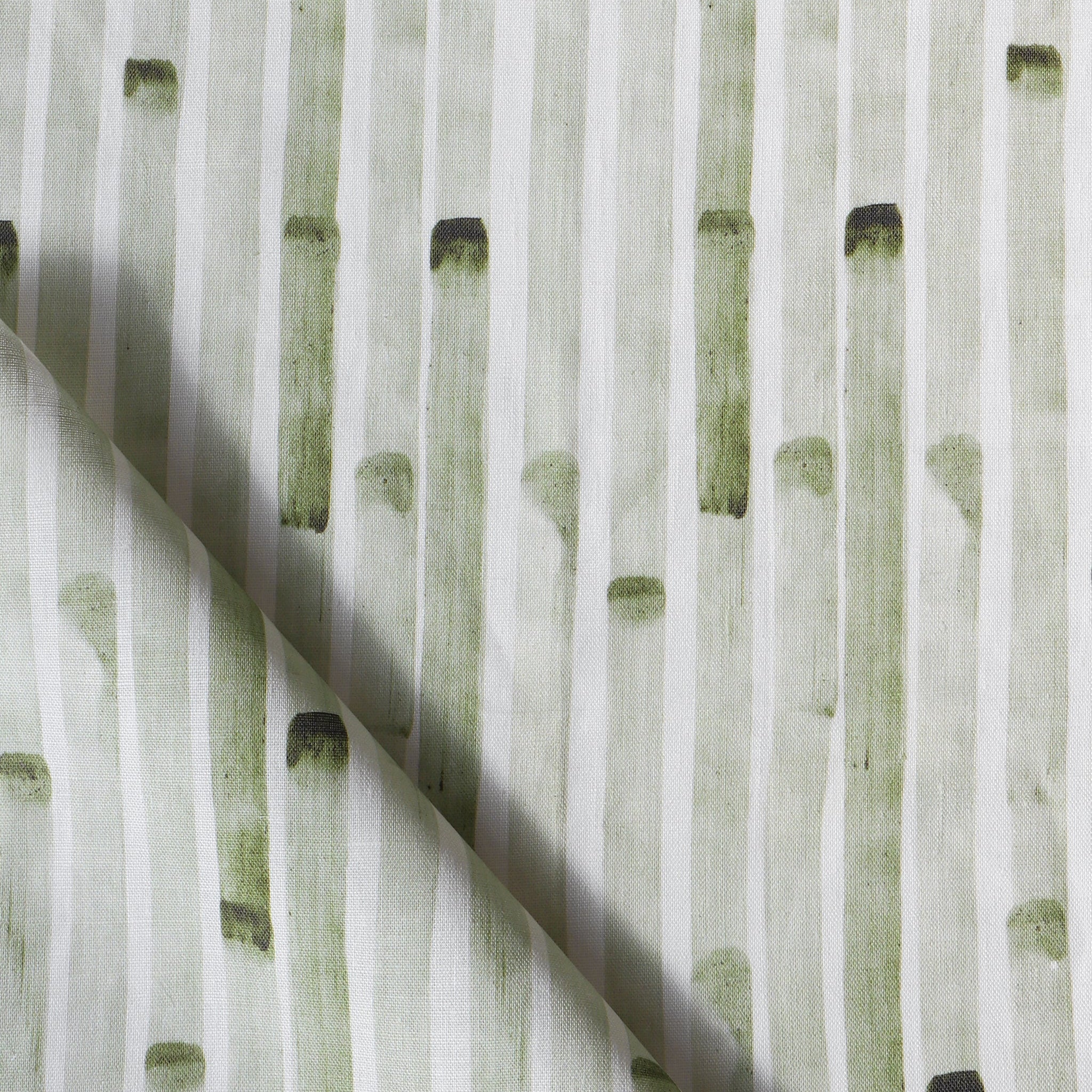 Detail of draped fabric in a painterly stripe print in olive on a white field.