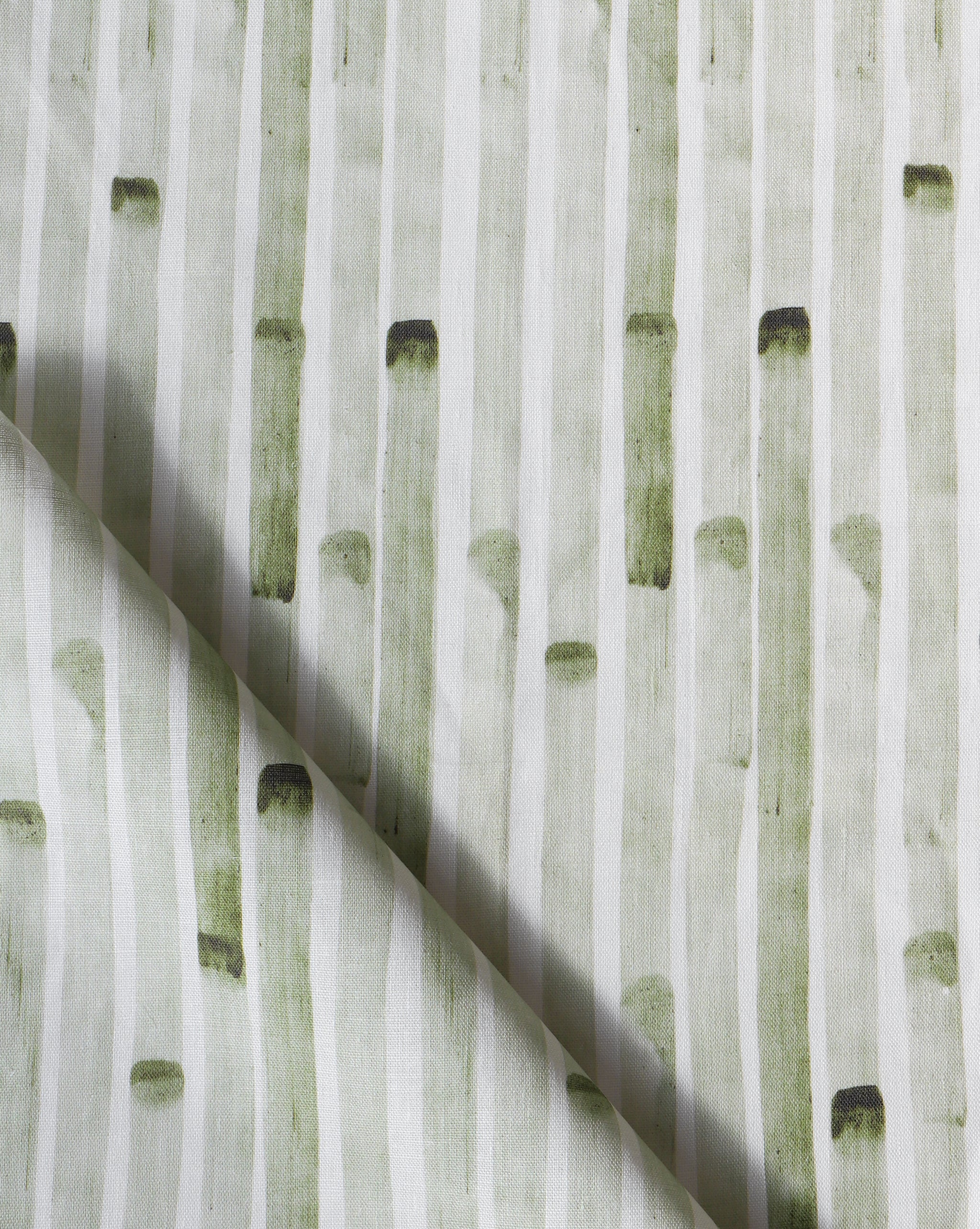 Detail of draped fabric in a painterly stripe print in olive on a white field.