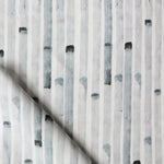 Detail of draped fabric in a painterly stripe print in gray on a white field.