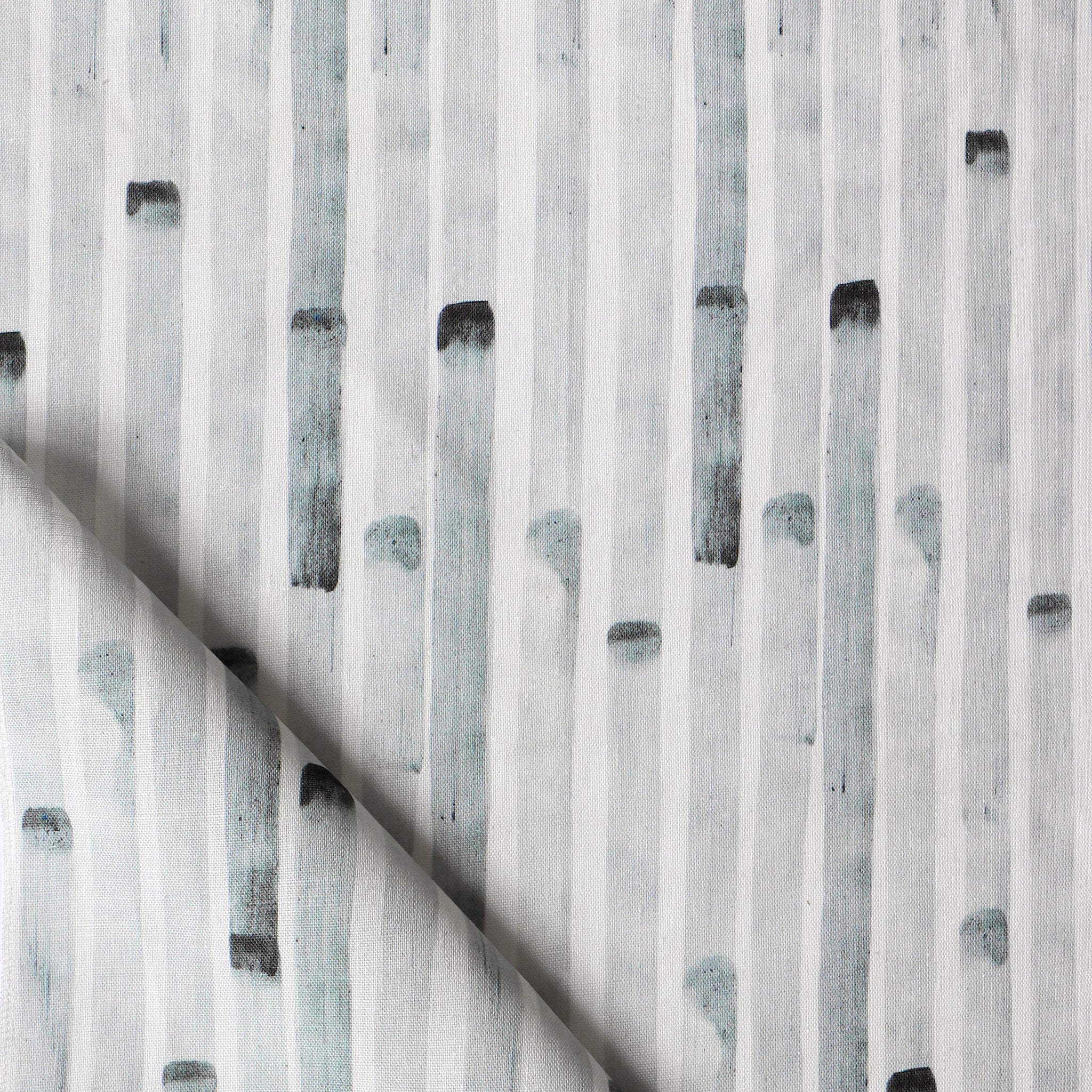 Detail of draped fabric in a painterly stripe print in gray on a white field.