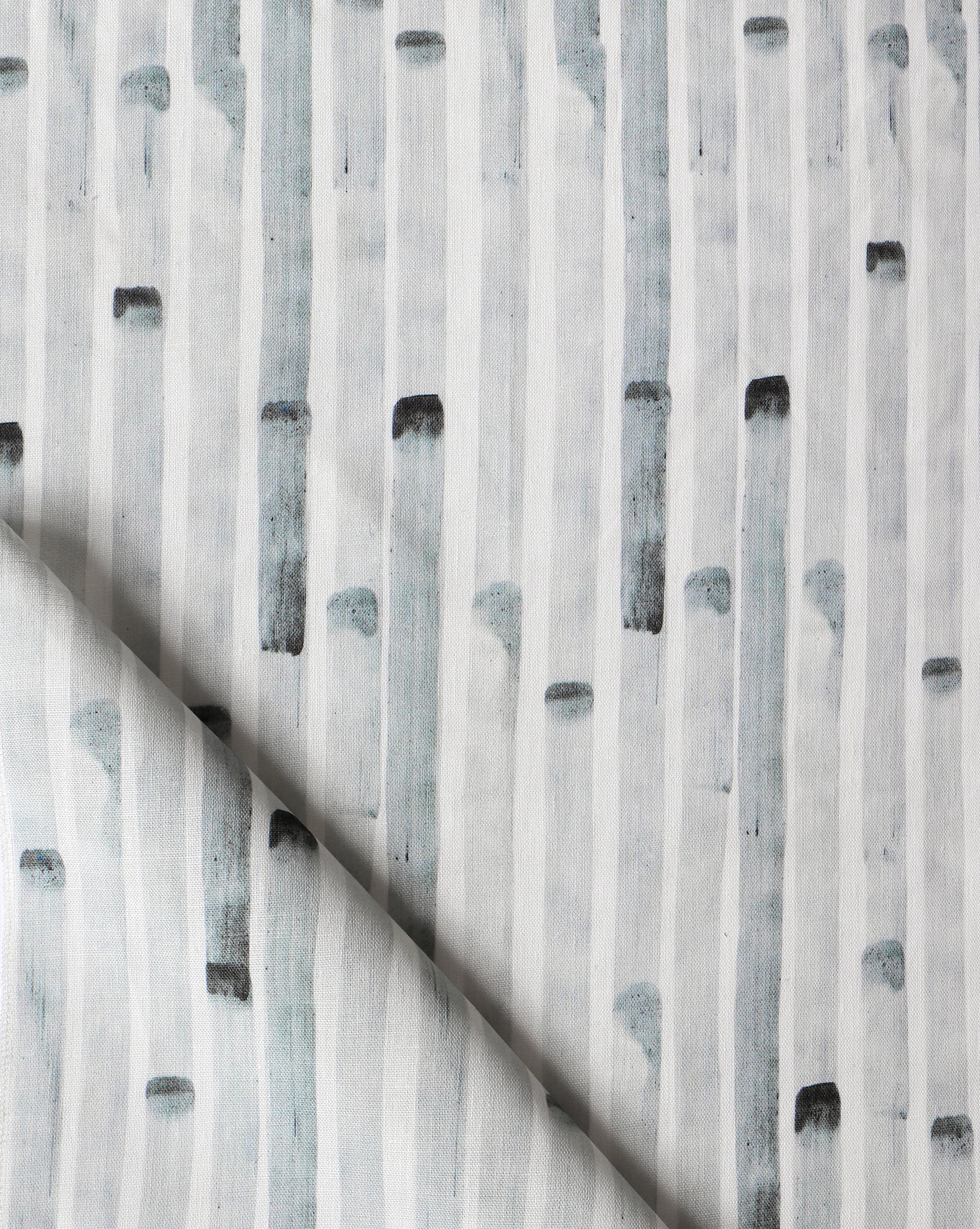 Detail of draped fabric in a painterly stripe print in gray on a white field.