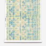 Partially unrolled wallpaper yardage in an abstract dyed grid print in mottled yellow, blue and white.