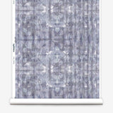 Partially unrolled wallpaper yardage in an abstract dyed grid print in mottled purple.