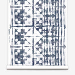 Partially unrolled wallpaper yardage in an abstract dyed grid print in mottled white and navy.