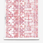 Partially unrolled wallpaper yardage in an abstract dyed grid print in mottled white, pink and red.