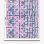 Partially unrolled wallpaper yardage in an abstract dyed grid print in mottled pink and navy.