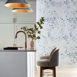 A modernist kitchen space with an accent wall papered in a painterly bandana print in navy and white.