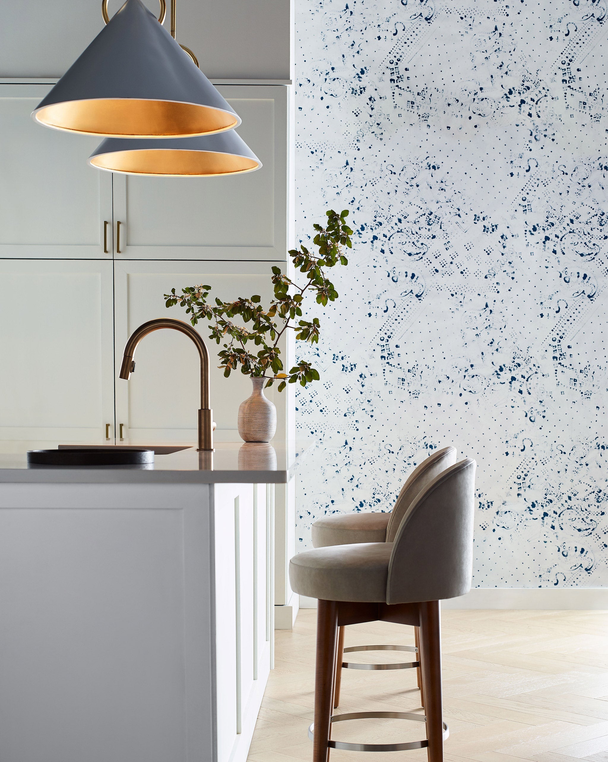 A modernist kitchen space with an accent wall papered in a painterly bandana print in navy and white.