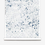 Partially unrolled wallpaper yardage in a painterly bandana print in navy on a white field.