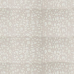 Detail of fabric in a batik splatter print in cream on a light gray field.