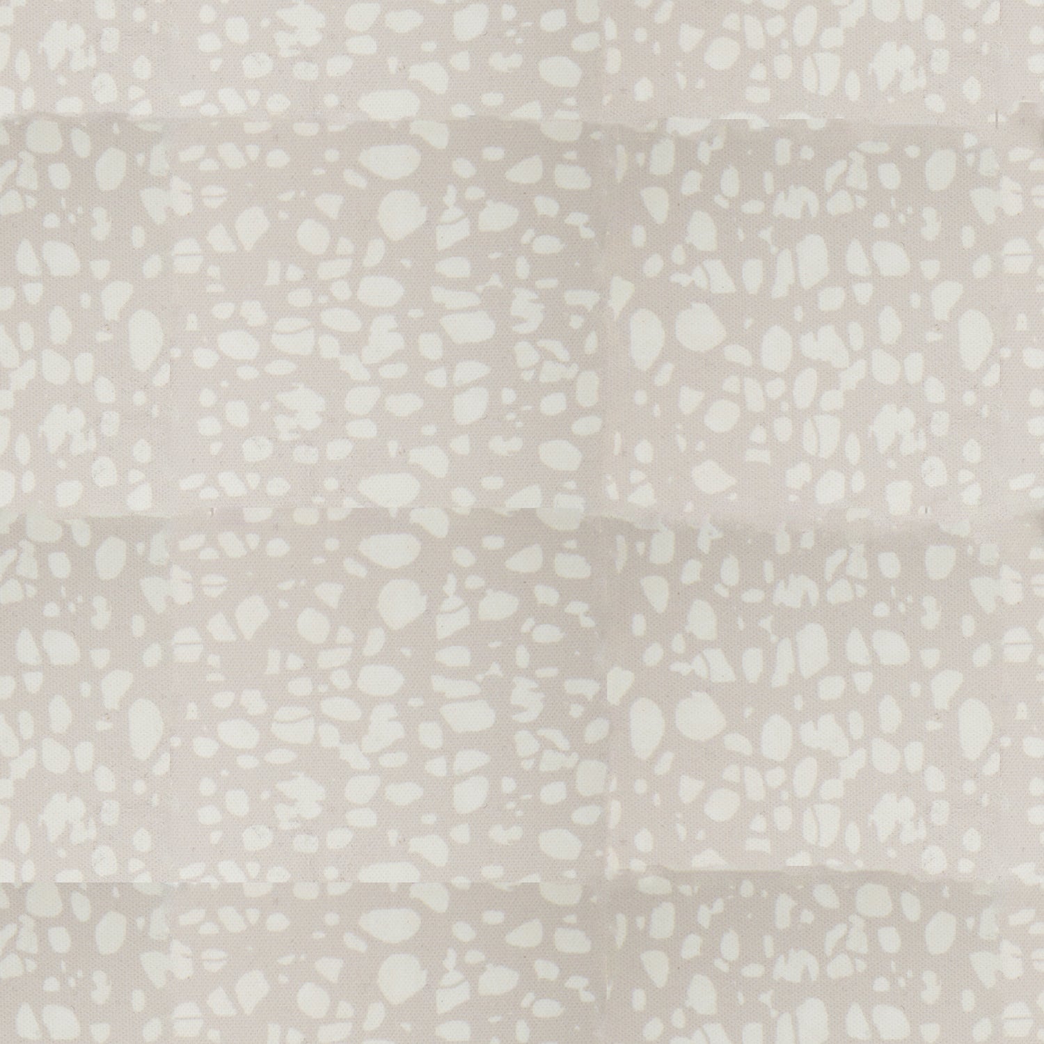 Detail of fabric in a batik splatter print in cream on a light gray field.