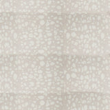 Detail of fabric in a batik splatter print in cream on a light gray field.