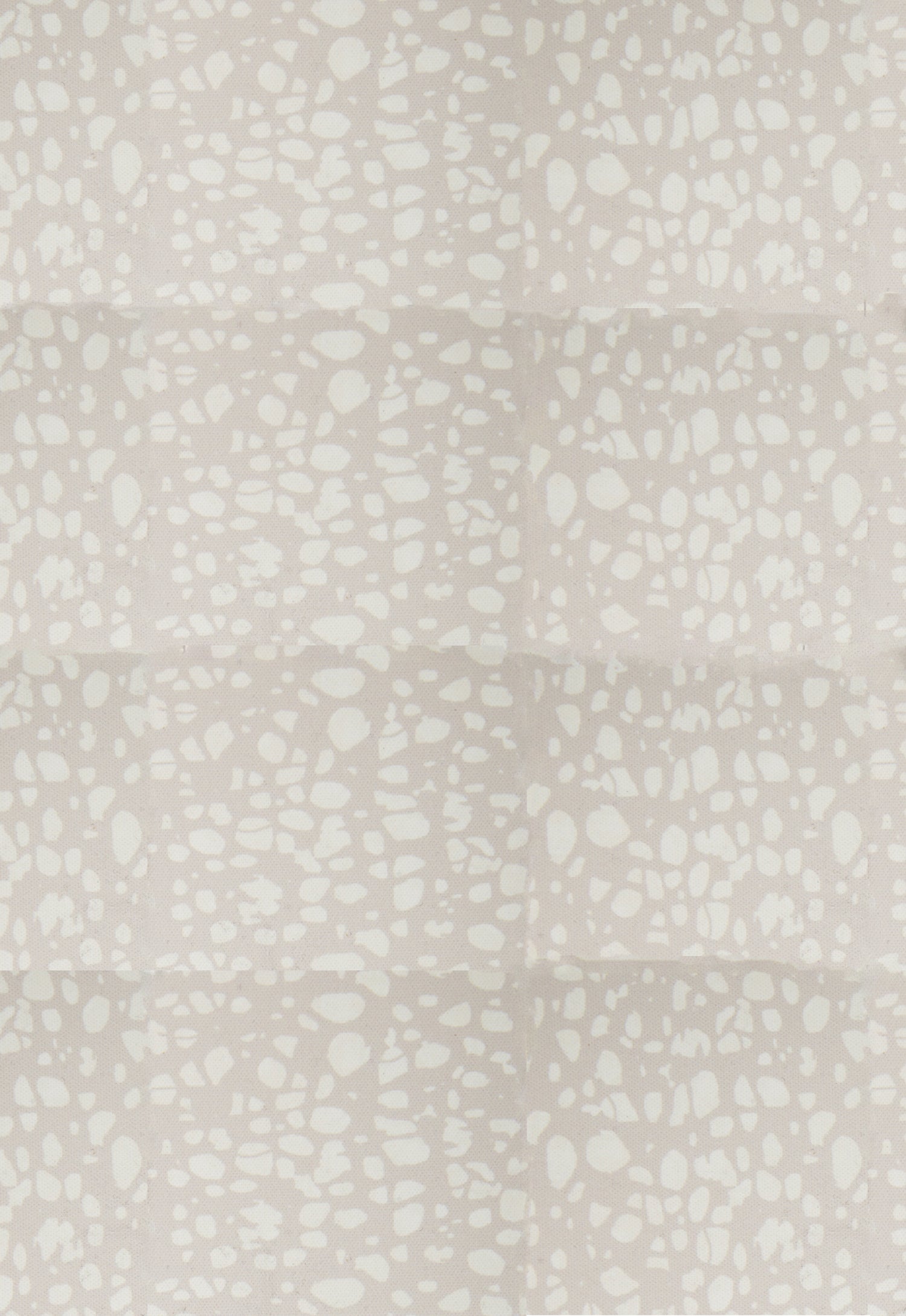 Detail of fabric in a batik splatter print in cream on a light gray field.