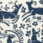 Close-up of fabric in a deer, leaf and flower print in navy on a white field.