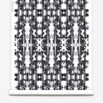 Partially unrolled wallpaper yardage in a painterly ikat print in black on a white field.