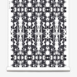 Partially unrolled wallpaper yardage in a painterly ikat print in black on a white field.