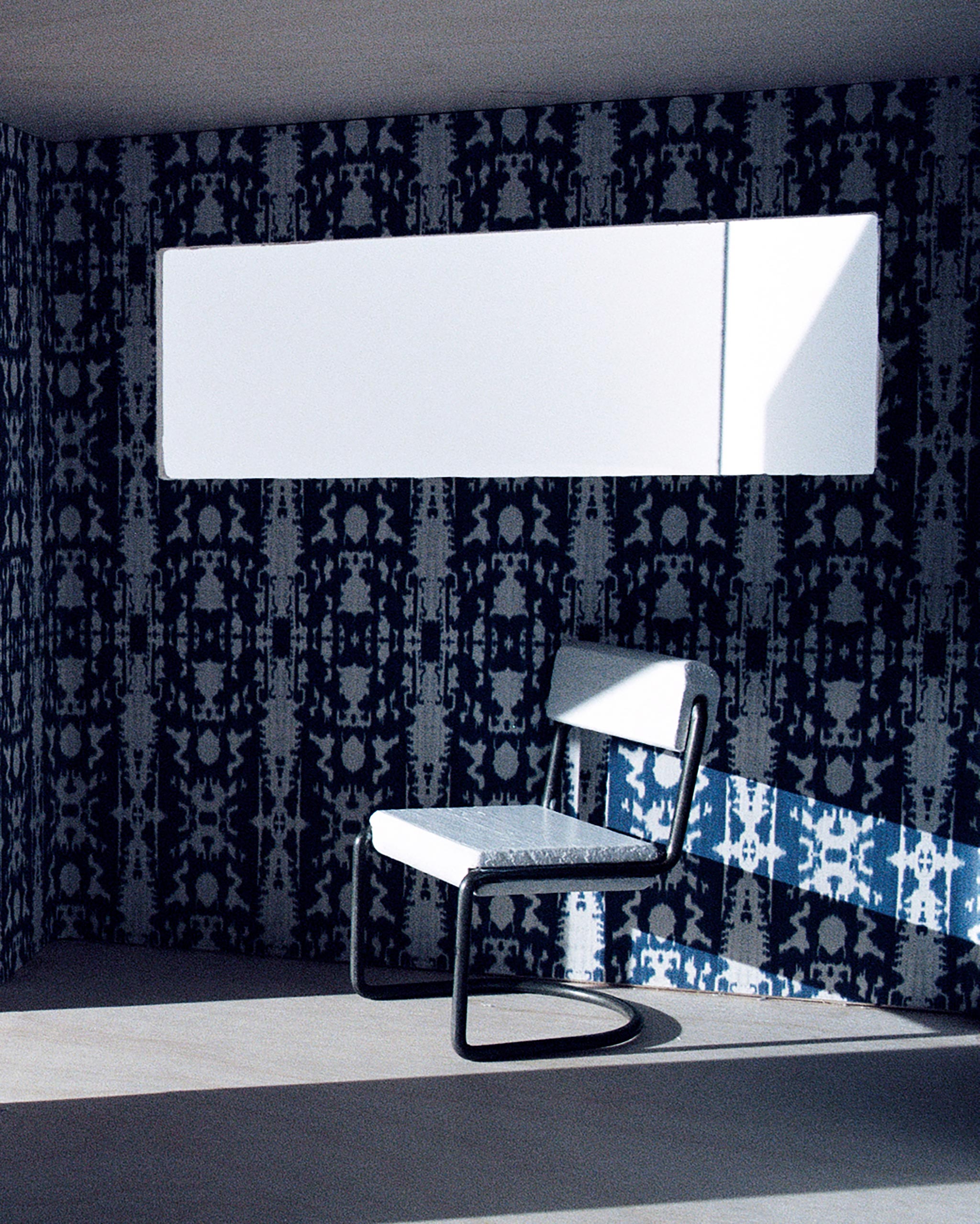 A modernist living tableau with walls papered in a painterly ikat print in blue and white.