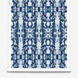 Partially unrolled wallpaper yardage in a painterly ikat print in blue and white.