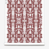 Partially unrolled wallpaper yardage in a painterly ikat print in rust and white.