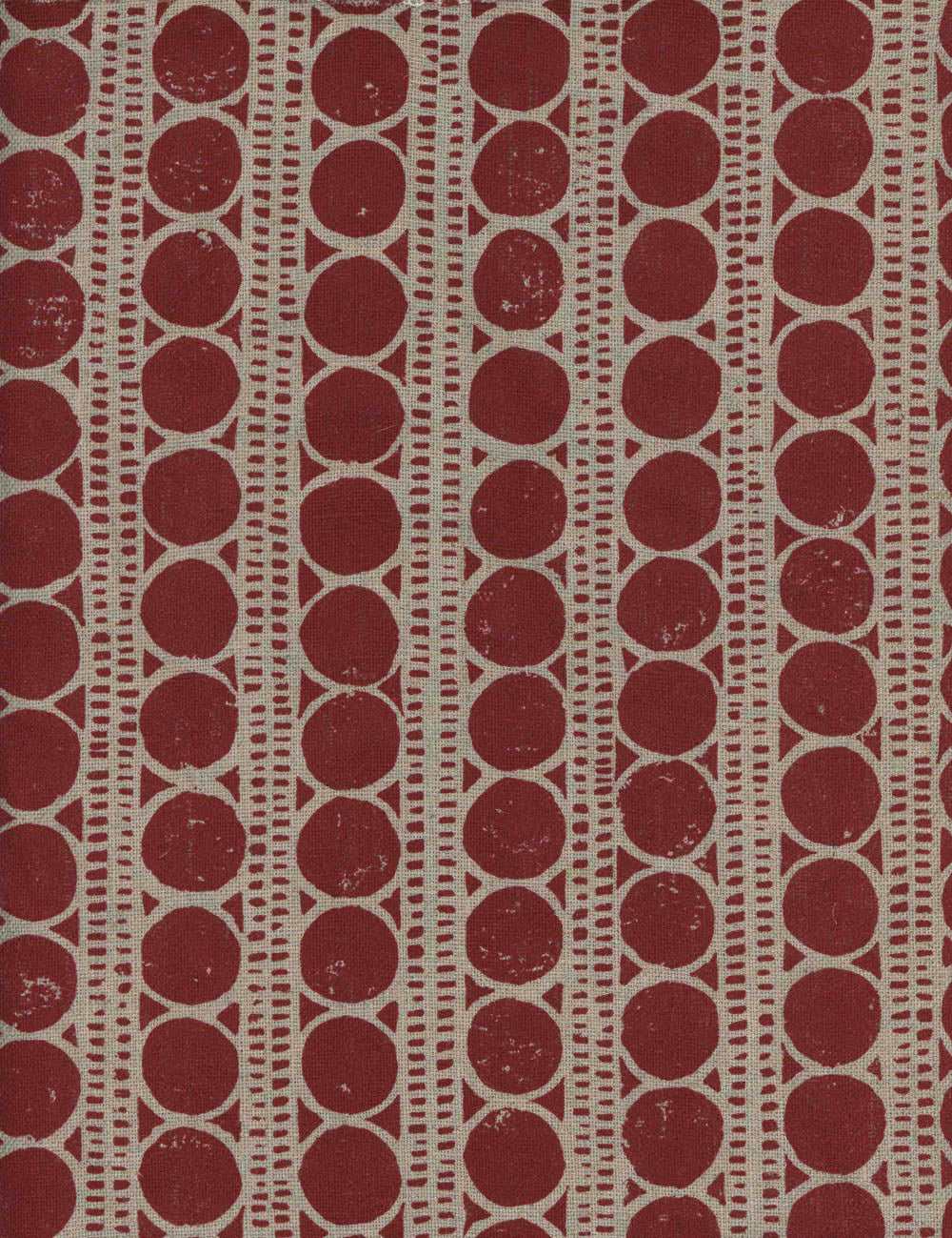 Detail of fabric in a circle and stripe print in tan on a red field.