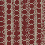 Detail of fabric in a circle and stripe print in tan on a red field.