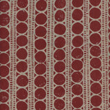 Detail of fabric in a circle and stripe print in tan on a red field.